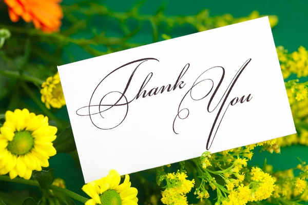 Gelbes Gänseblümchen, Gerbera und Karte signiertes Dankeschön auf grünem Hintergrund — Stockfoto