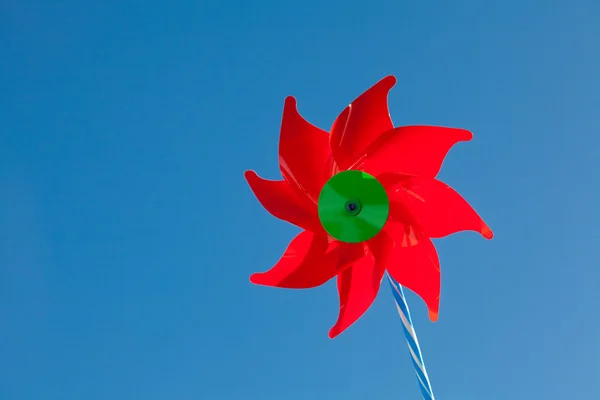 Игрушечный красный ветряк на фоне голубого неба — стоковое фото