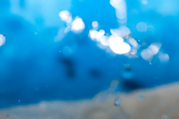 Wasserspritzer in einer Tasse auf blauem Hintergrund — Stockfoto