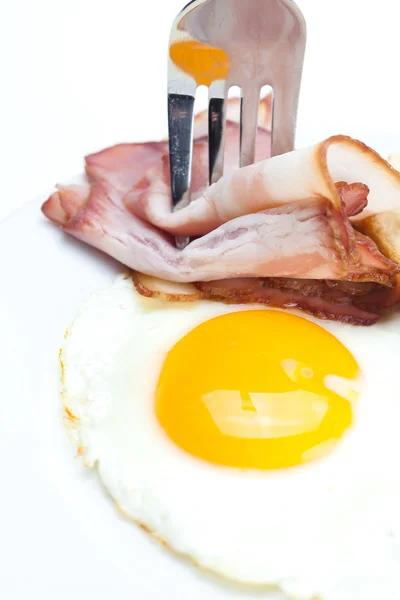 Slanina se smaženými vejci na talíř, vidlice a chléb izolovaných na w — Stock fotografie