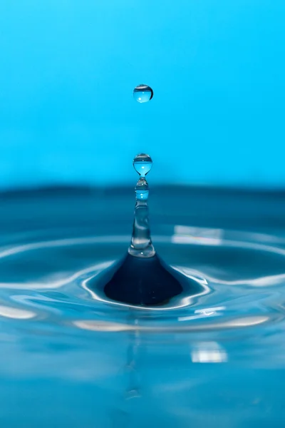 Vattendroppe och stänk på en blå bakgrund — Stockfoto