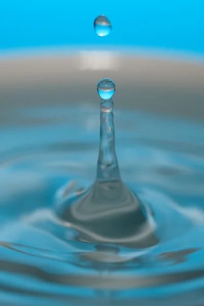 Wassertropfen und Spritzer auf blauem Hintergrund — Stockfoto