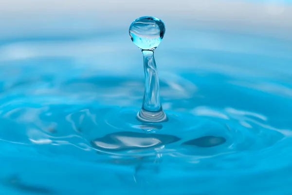 Vattendroppe och stänk på en blå bakgrund — Stockfoto