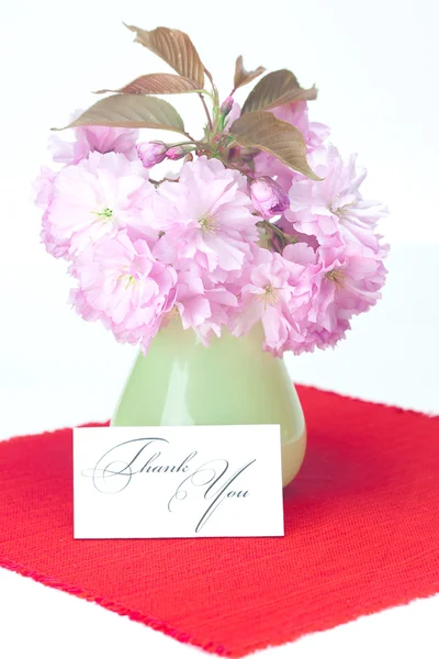 Sakura kwiatów w wazonie i kartę podpisał dziękuję na czerwony bac — Zdjęcie stockowe