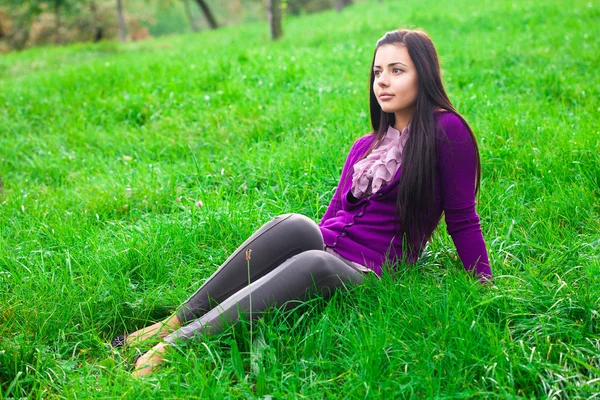 美しい若い女性は緑の芝生の上に横たわる — Stockfoto
