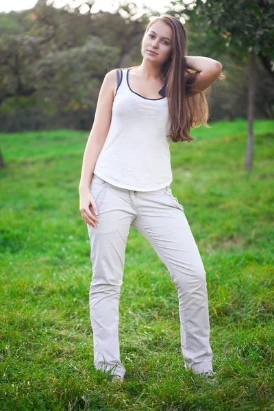 Bela jovem mulher de pé na grama verde — Fotografia de Stock