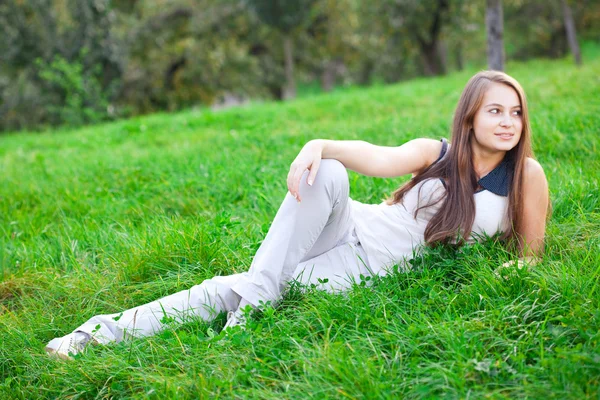 美丽的年轻女子躺在绿草地上 — 图库照片