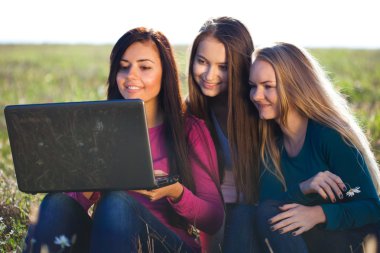 alan o oturan bir dizüstü bilgisayar ile üç genç güzel kadın