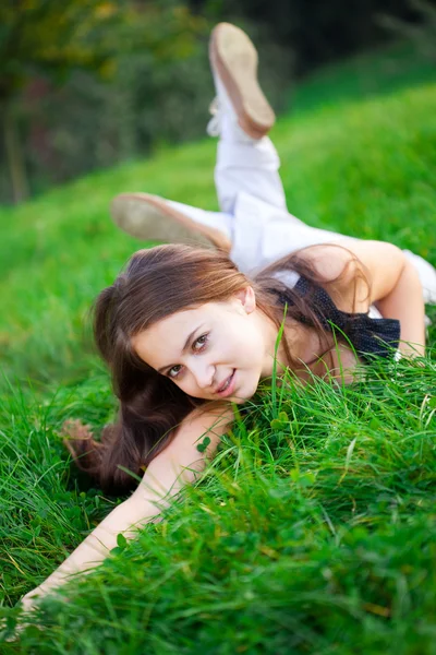 Piękna młoda kobieta, leżąc na zielonej trawie — Zdjęcie stockowe