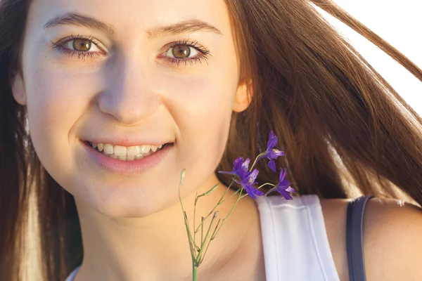 फुलांच्या मैदानीसह एक सुंदर तरुण स्त्रीचे पोर्ट्रेट — स्टॉक फोटो, इमेज
