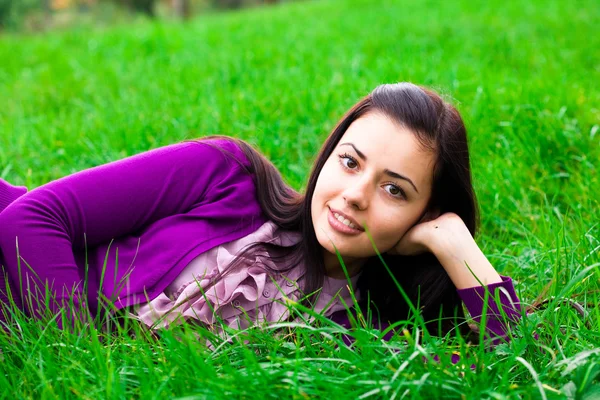 Beautiful young woman lying on green grass — Stock Photo, Image