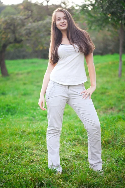 美しい若い女性は緑の芝生の上に立って — ストック写真