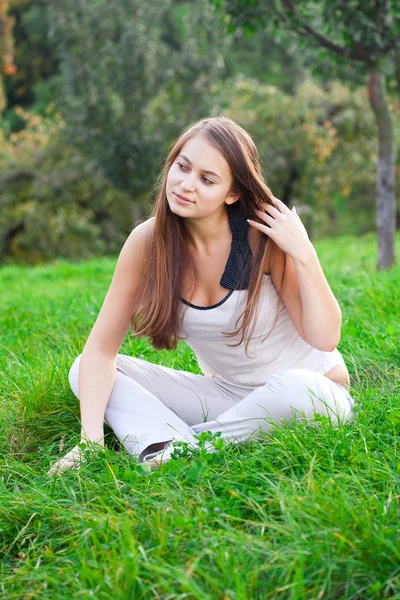 Yeşil çimenlerin üzerinde oturan güzel genç kadın — Stok fotoğraf