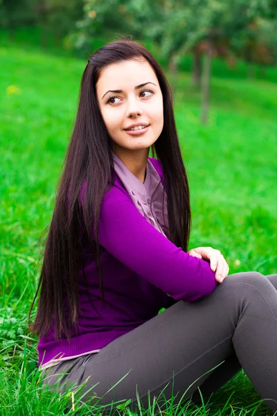 Schöne junge Frau sitzt auf grünem Gras — Stockfoto