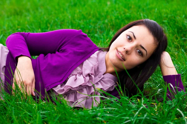 美しい若い女性は緑の芝生の上に横たわる — Stockfoto