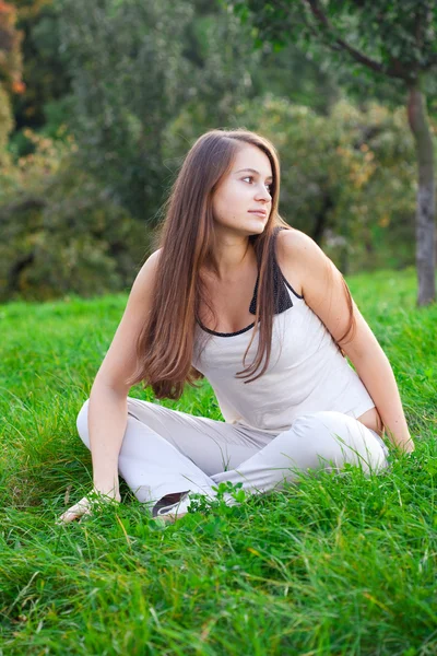 Bella giovane donna seduta su erba verde — Foto Stock