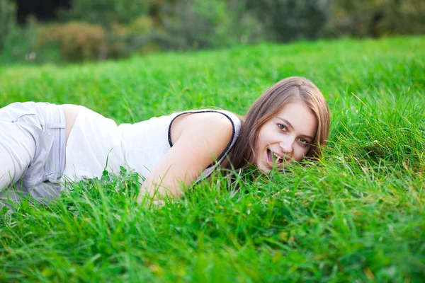 Mooie jonge vrouw liggend op groen gras — Stockfoto