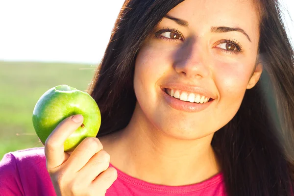 Retrato de una hermosa joven con manzana al aire libre — Foto de Stock