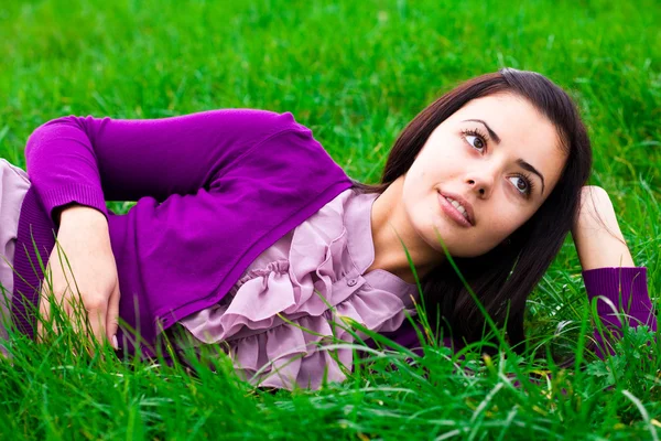Bella giovane donna sdraiata su erba verde — Foto Stock
