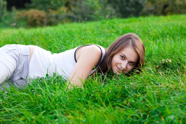 Schöne junge Frau auf grünem Gras liegend — Stockfoto