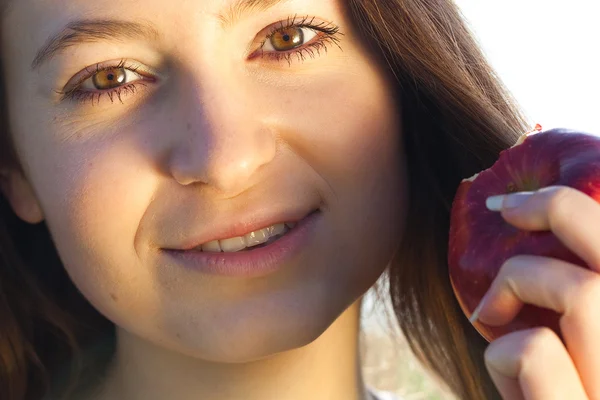 Портрет красивой молодой женщины с яблоком на открытом воздухе — стоковое фото
