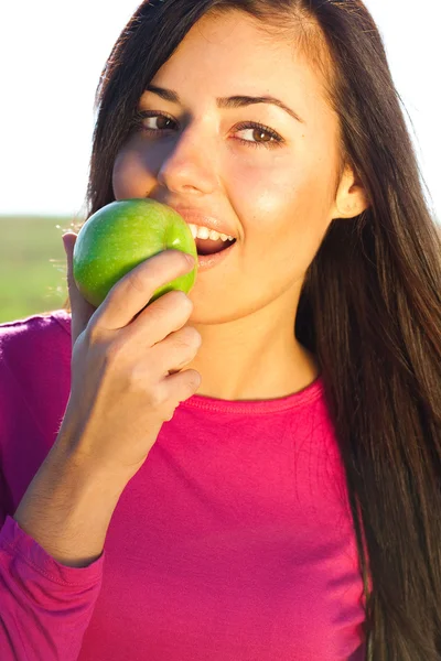 Портрет красивой молодой женщины с яблоком на открытом воздухе — стоковое фото