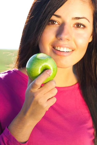 Retrato de una bella mujer joven con manzana al aire libre — Stockfoto