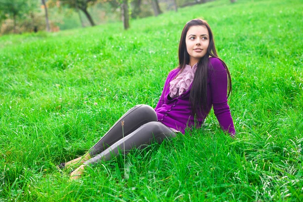 สาวสวยนั่งบนหญ้าสีเขียว — ภาพถ่ายสต็อก