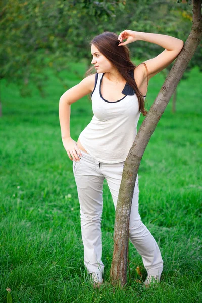 Schöne junge Frau steht auf grünem Gras — Stockfoto
