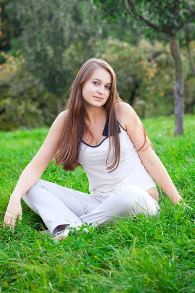 Krásná mladá žena sedící na zelené trávě — Stock fotografie