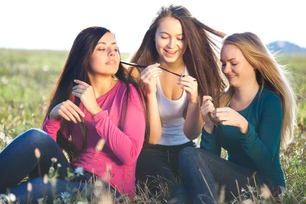 Tres mujeres jóvenes y hermosas sentadas en un campo en el cielo — Foto de Stock