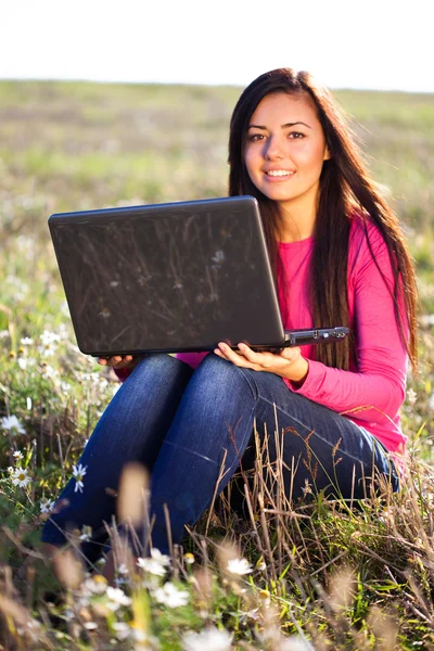 Gökyüzü alanında oturmuş bir dizüstü bilgisayar ile genç güzel kadın — Stok fotoğraf