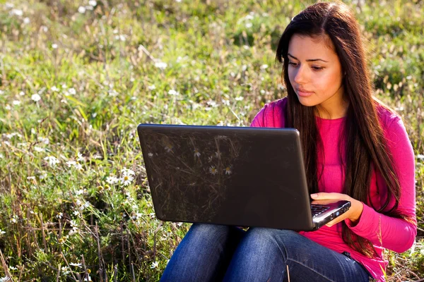 Όμορφη κοπέλα με ένα φορητό υπολογιστή που κάθεται στο πεδίο στον ουρανό — Φωτογραφία Αρχείου