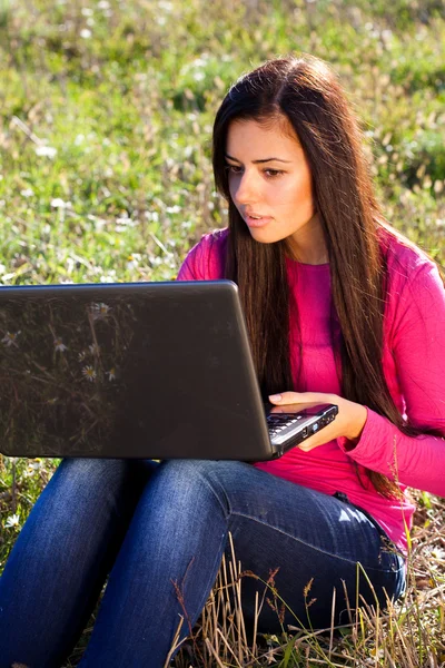 Joven hermosa mujer con un ordenador portátil sentado en el campo en el cielo —  Fotos de Stock