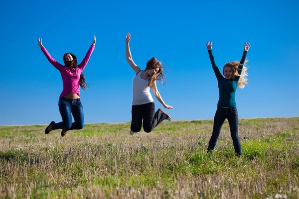 Три молодих красива жінка стрибає в поле проти s — стокове фото