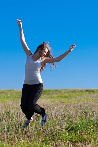 Joven mujer hermosa saltando al campo contra el cielo — Foto de Stock