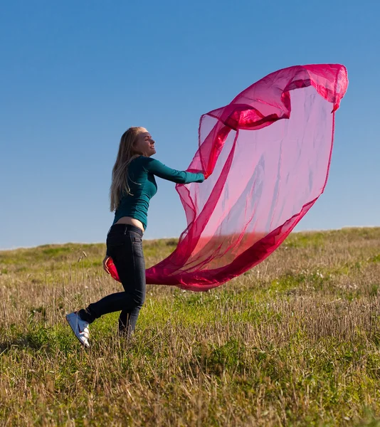 Ung vacker kvinna hoppa med vävnad i fältet mot — Stockfoto
