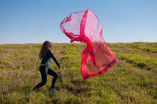 Joven hermosa mujer saltando con tejido en el campo contra — Foto de Stock