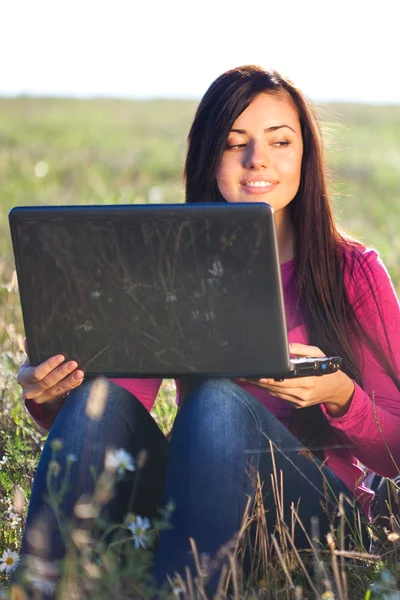 Mladá krásná žena s notebookem sedět v poli na obloze — Stock fotografie