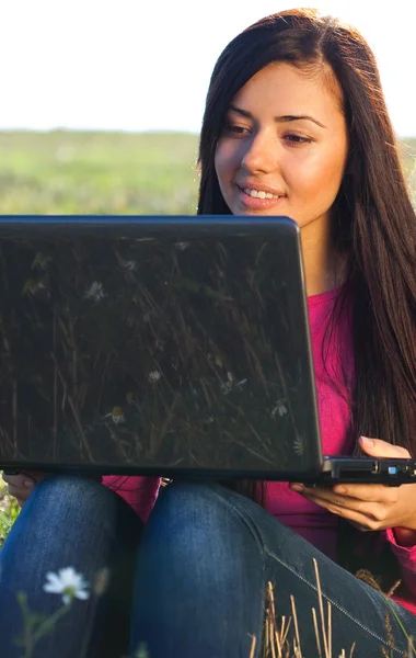 하늘에 있는 필드에 앉아 노트북으로 젊은 아름 다운 여자 — 스톡 사진