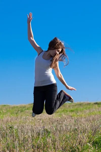 Ung vacker kvinna hoppa i fältet mot himlen — Stockfoto