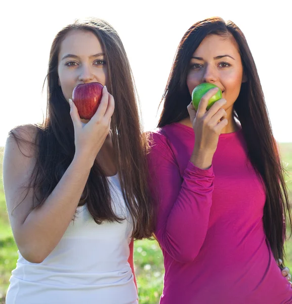 Retrato de duas jovens mulher bonita com maçã no céu de volta — Fotografia de Stock
