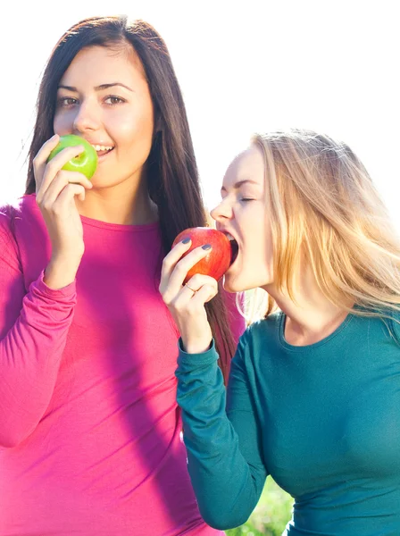 Portret of two young beautiful woman with apple on the sky back — Stock Photo, Image