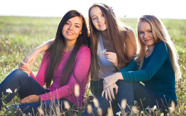Trzech młodych piękna kobieta siedzi w polu backg niebo — Zdjęcie stockowe
