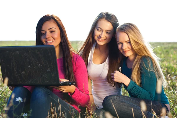 三个年轻美丽的女人坐在外地 o 一台笔记本电脑 — 图库照片