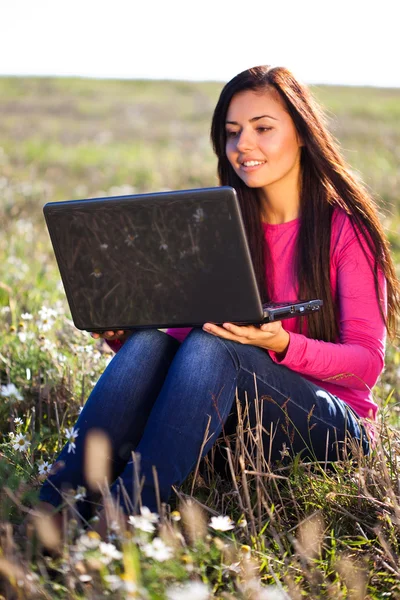 Όμορφη κοπέλα με ένα φορητό υπολογιστή που κάθεται στο πεδίο στον ουρανό — Φωτογραφία Αρχείου