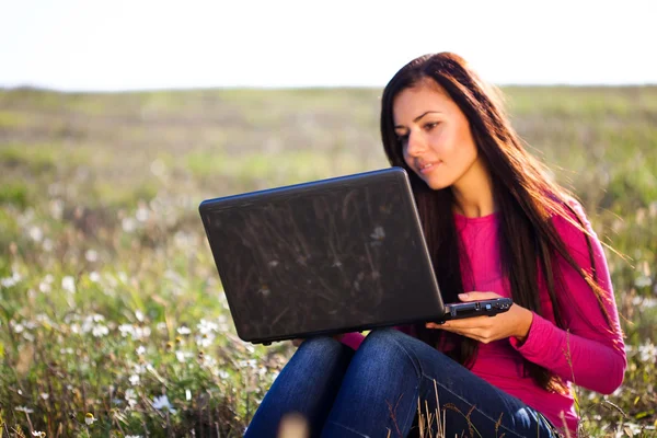 Mladá krásná žena s notebookem sedět v poli na obloze — Stock fotografie