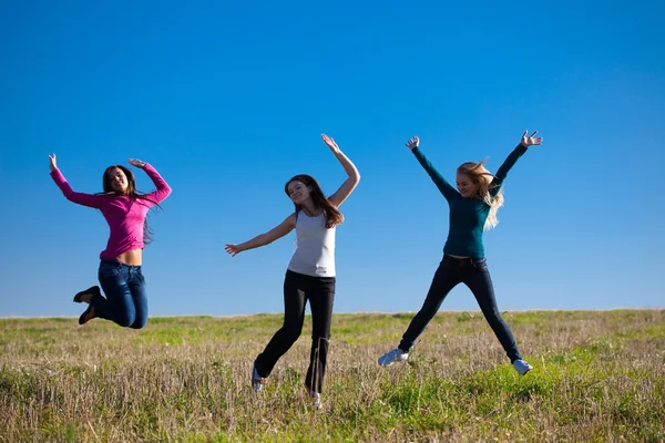 Tři mladá krásná žena skákat do pole proti s — Stock fotografie