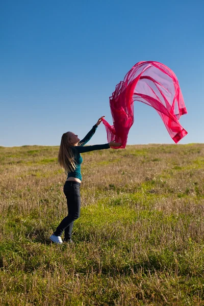 Ung vacker kvinna hoppa med vävnad i fältet mot — Stockfoto