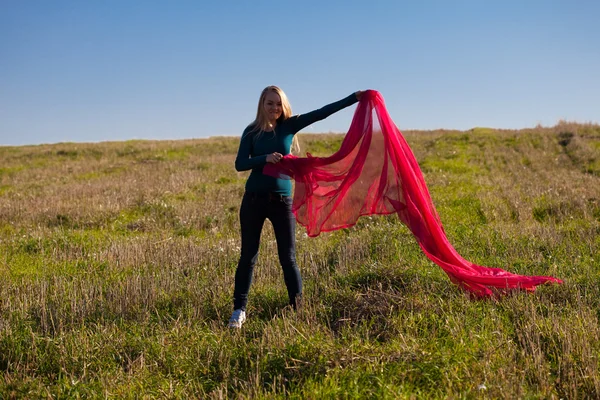 Giovane bella donna che salta con tessuto nel campo contro — Foto Stock